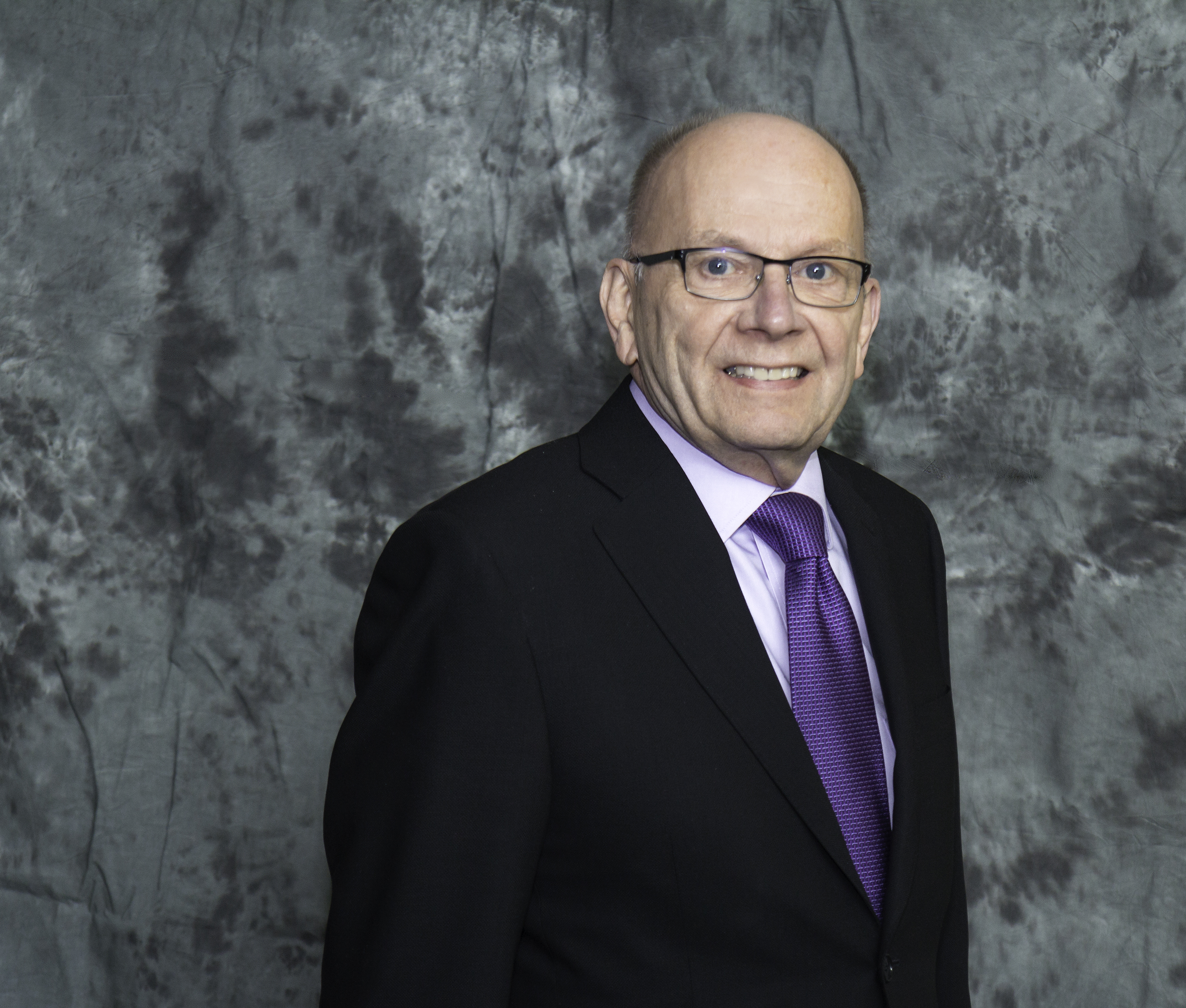 Headshot of George Curry in a black suit and purple tie